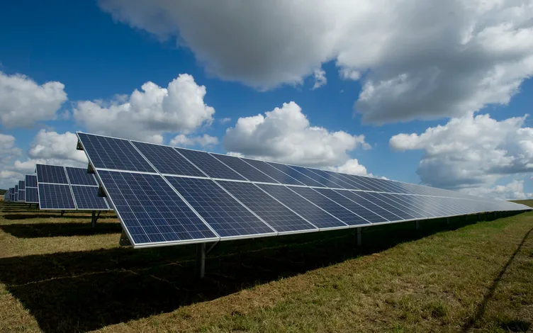 Rows of solar panels under a bright sky