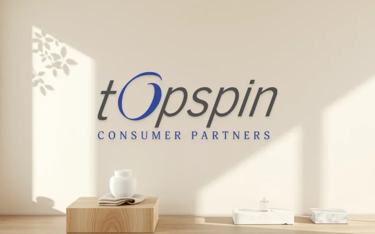 Topspin Consumer Partners lettering on a warm plaster wall above a ceramic jar and linen